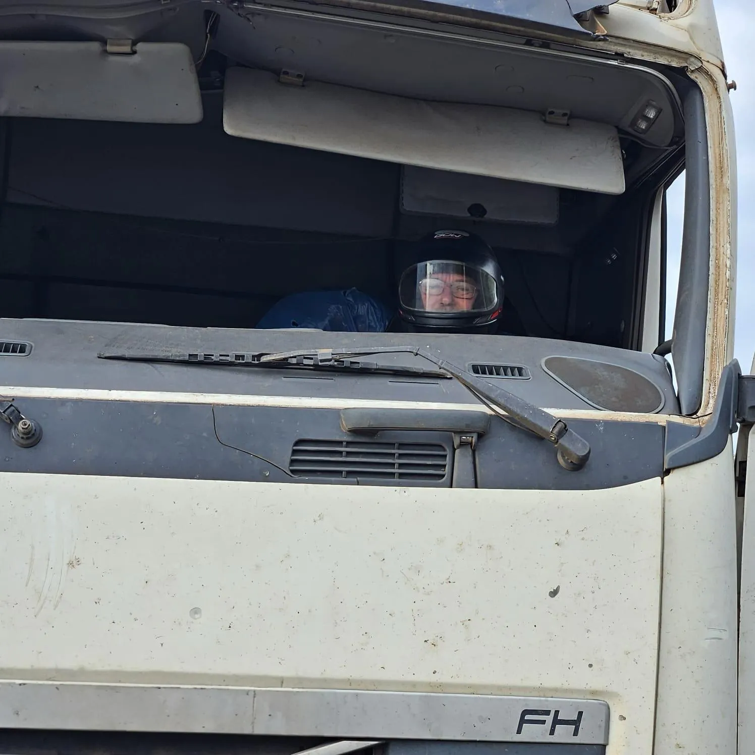 PRF flagra carreta sem para-brisas, caminhoneiro de capacete e peças amarradas com cordas